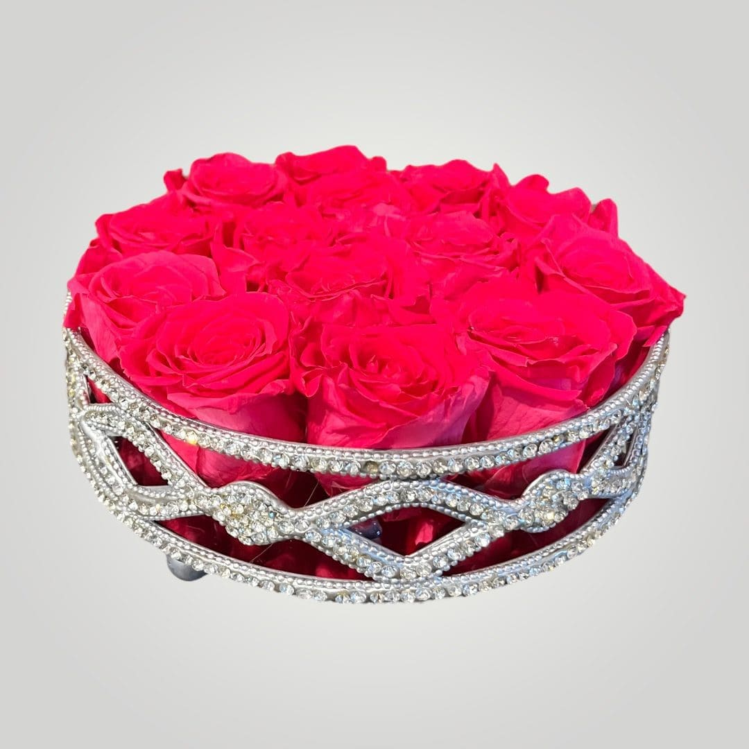 A round silver container with pink roses inside of it.