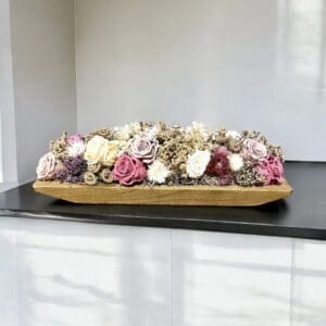 A wooden tray with flowers on top of the table.