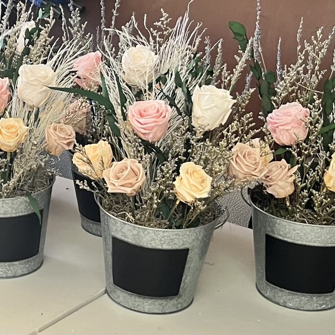 A group of flowers in pots on top of a table.