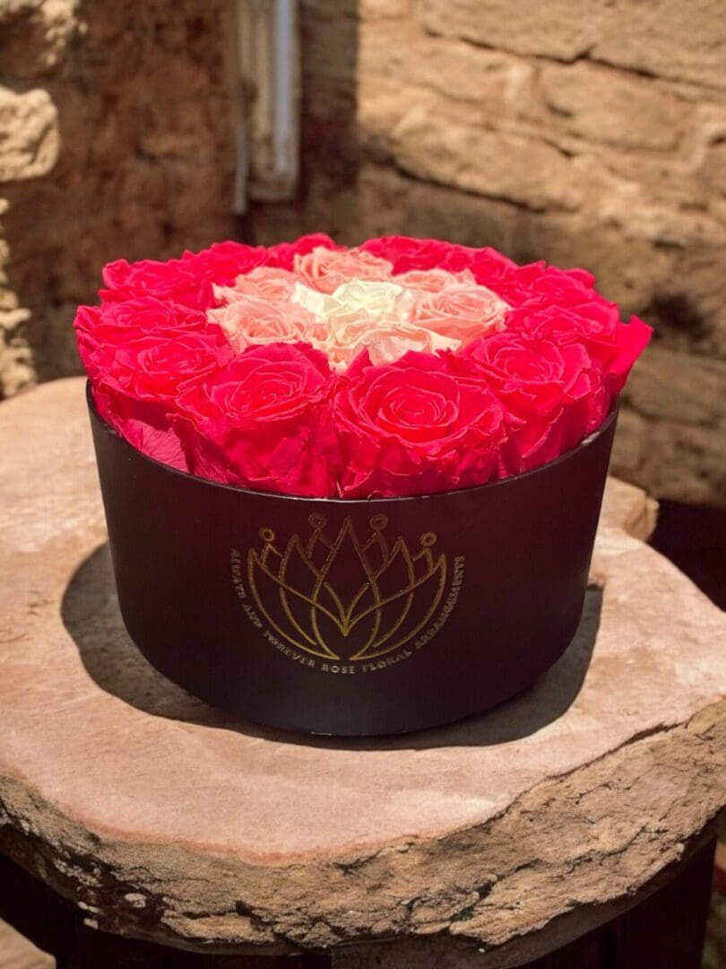 A round box of roses on top of a wooden table.